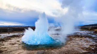 The Golden Circle on the Island Round Trip: A buzzing and steaming Geysir in a carous landscape on Iceland