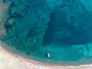 In the sea in front of the Plage de Saleccia swimming a boat, in the water swimming a few people and some are located on the beach. Corsica is also a good choice for the Caribbean in Europe.
